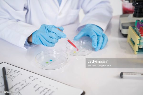 Scientist preparing blood grouping compounds with laboratory glassware.